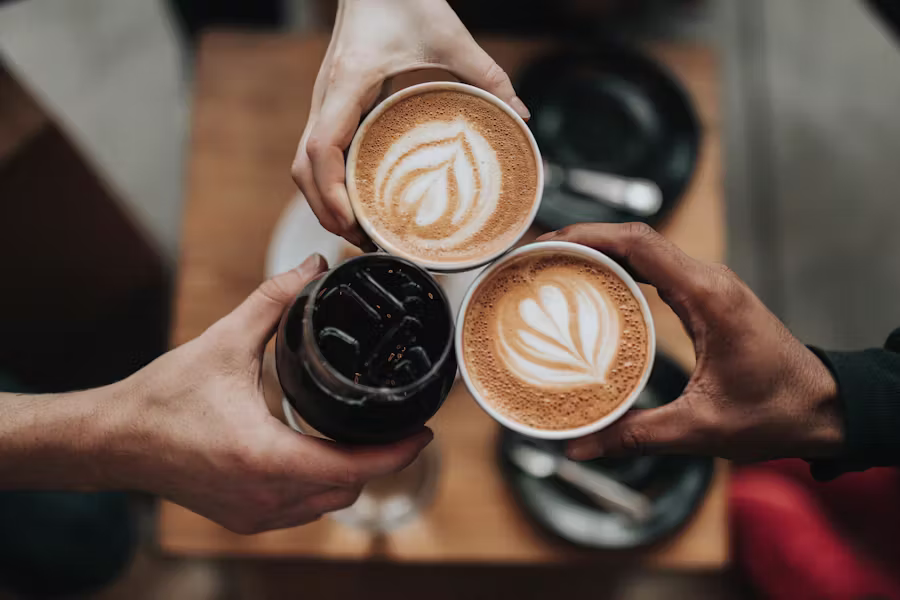 Three hands toasting with cups of coffee